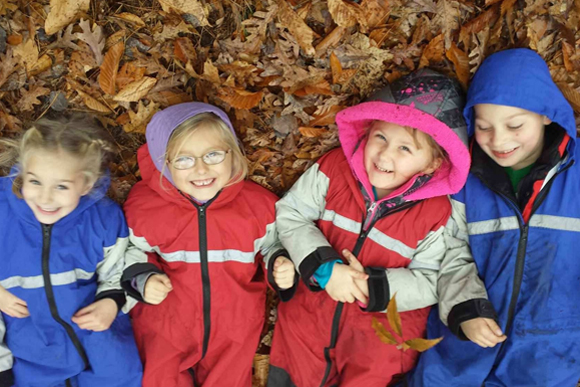 Students play in leaves during their time outdoors in the autumn.
