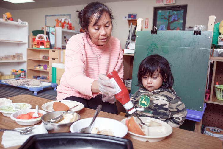 A little one gets help with lunch. Photo by Autumn Johnson