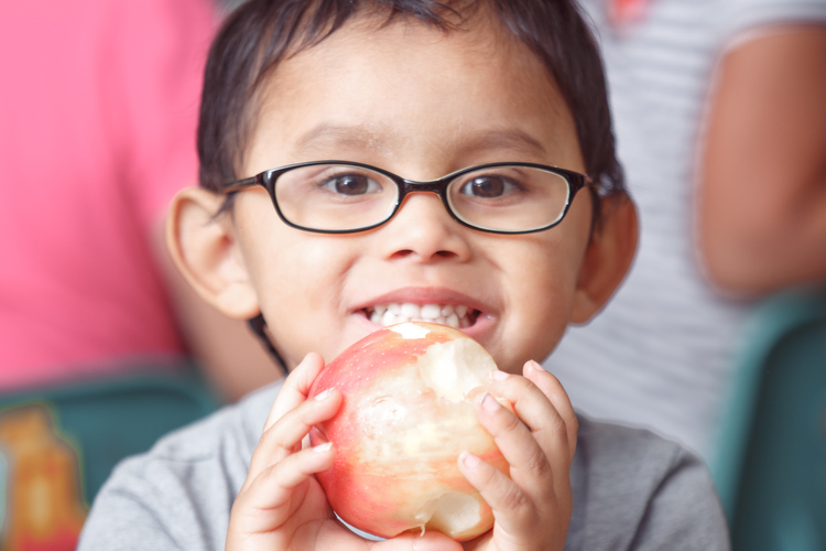 Enjoying a Michigan apple for lunch at the Head Start Program in Sparta. Photo by Autumn Johnson