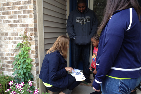 Erica Mausolf (kneeling) and Meredith Washeleski of Sycamore Elementary (standing) visit with a kindergarten family in their home before the first day of school.