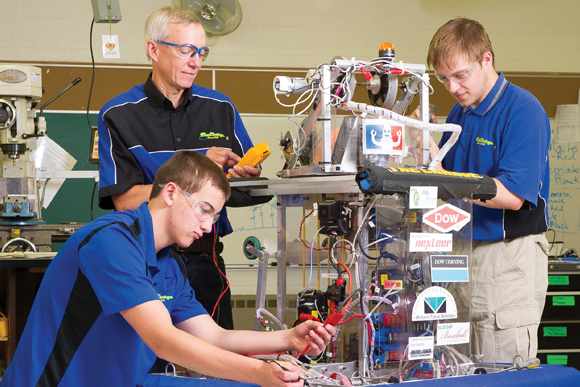 Mike Rehberg (middle) is one of several FIRST Robotics mentors who dedicates hundreds of hours every year to help students, such as the ones pictured here, foster important STEM skills. 