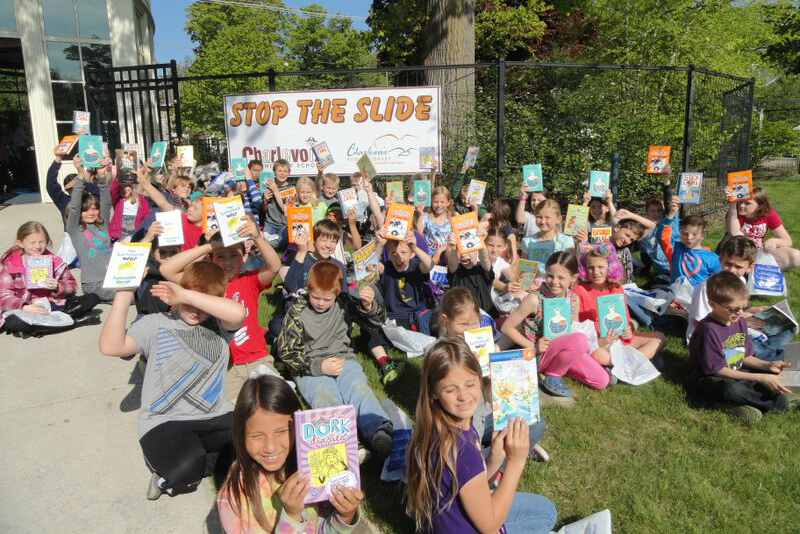 Students hold their summer reading books high on the last day of school.