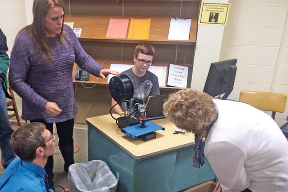 Marquette Area Public Schools Board Trustee Matthew Williams, bottom left, and Secretary/Treasurer Jean Hetrick, right, watch a 3-D printing demonstration by members of Marquette Senior High School�s Digital Makers Club presented by science teacher R